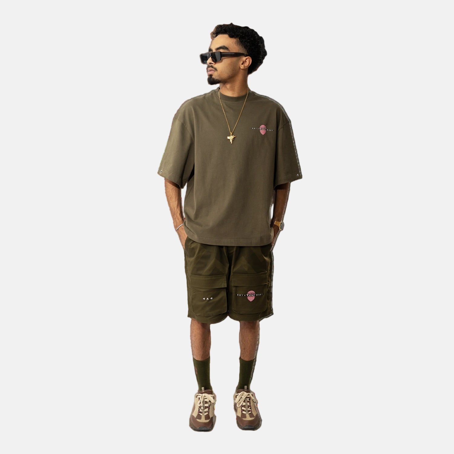 Man wearing an olive green t-shirt and shorts set with a plain background